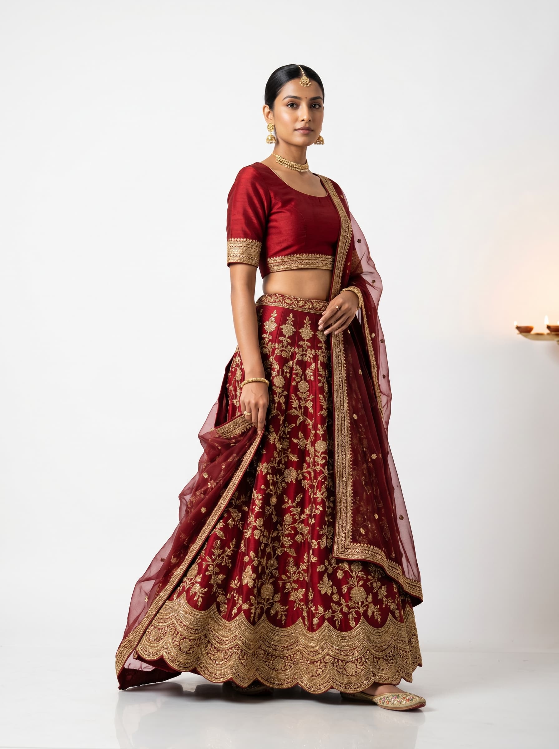 Indian model in red zardosi lehenga with diya backdrop — Diwali catalog photography